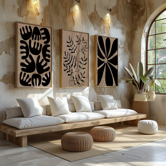 A triad of bold black abstract and organic forms on beige canvases, artfully arranged in a bright, airy room with rustic details.