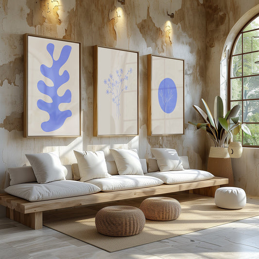 A trio of chic blue botanical prints, featuring a bold leaf, delicate flowers, and a round botanical design, in a modern minimalist living room.