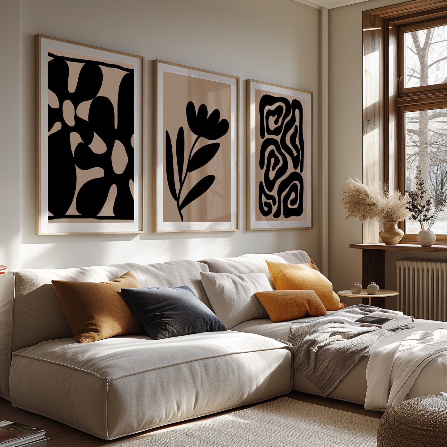 An elegant trio of art prints in black and beige, featuring abstract shapes and stylized floral designs in a modern bedroom.