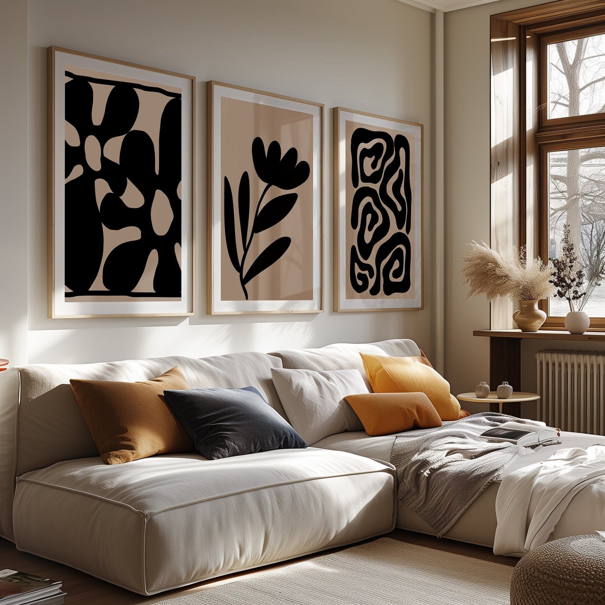 An elegant trio of art prints in black and beige, featuring abstract shapes and stylized floral designs in a modern bedroom.