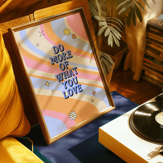 A motivational wall art poster with the text &quot;Do More of What You Love&quot; set against a colorful, wavy background with flowers and stars.