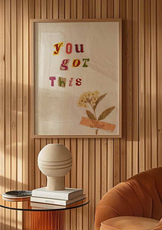 A motivational poster with the text &quot;You Got This&quot; in colorful letters with a dried flower taped to the background, perfect for encouraging positivity.