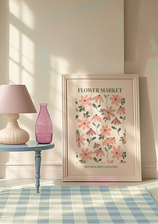 A framed Flower Market poster featuring pink floral illustrations, displayed against a pink tiled wall with a wooden shelf, adding a charming cottagecore touch to the space.