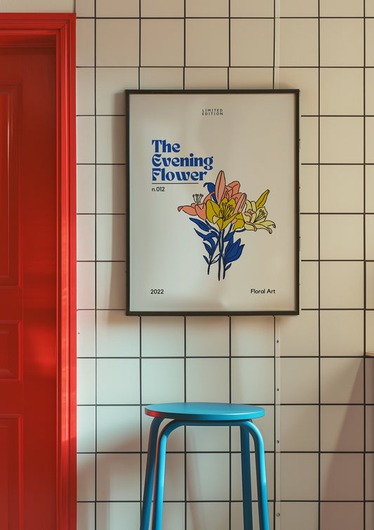 A stylish and vibrant poster titled &quot;The Evening Flower&quot; with colorful floral artwork, framed in black, and displayed on a tiled wall with a red door and blue stool in the foreground.