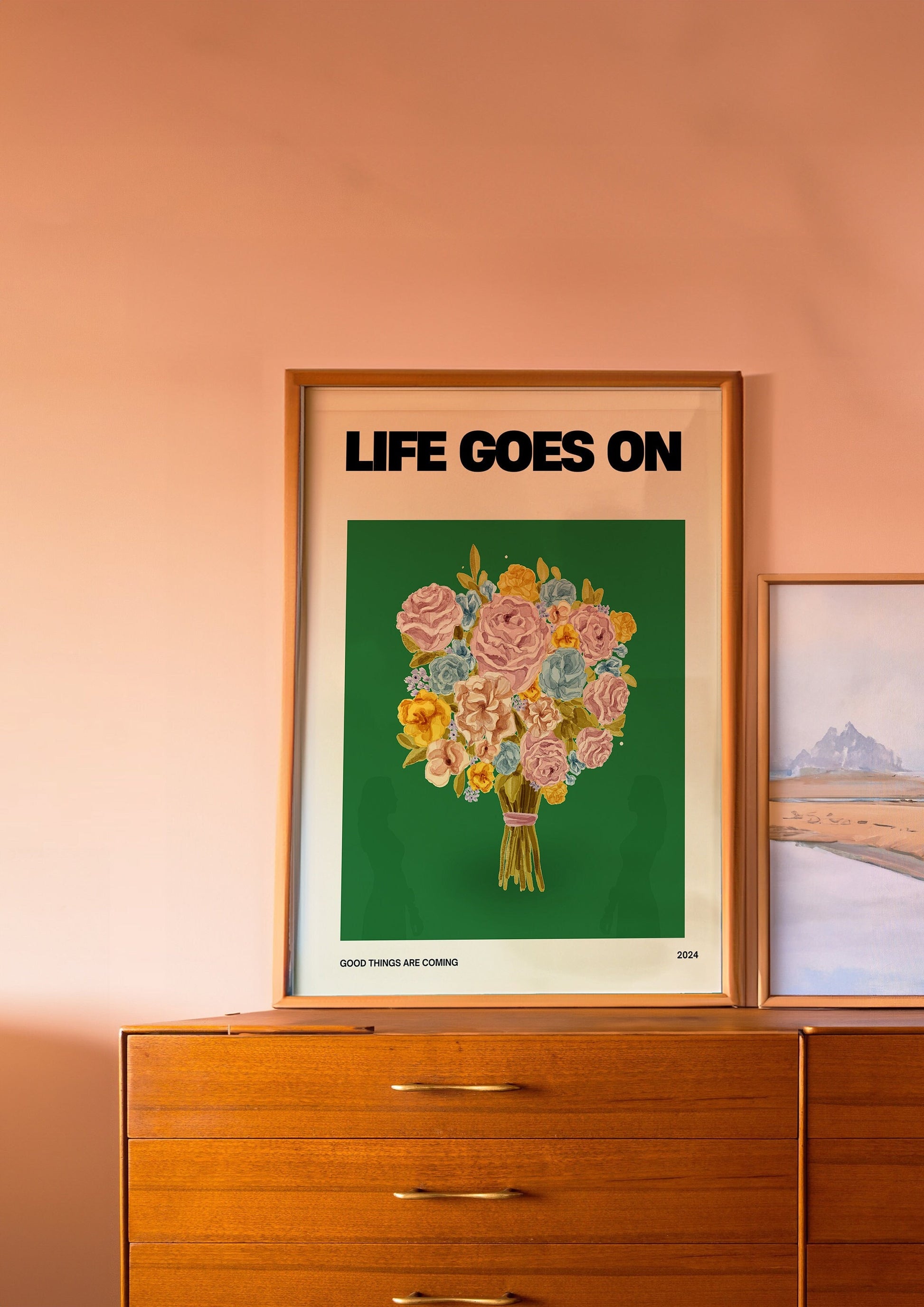 A motivational poster titled &quot;Life Goes On,&quot; featuring a vibrant bouquet of flowers against a deep green background. The phrase &quot;Good Things Are Coming&quot; is written below the floral arrangement