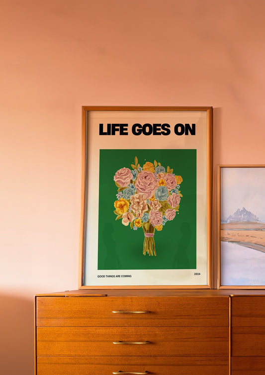 A motivational poster titled &quot;Life Goes On,&quot; featuring a vibrant bouquet of flowers against a deep green background. The phrase &quot;Good Things Are Coming&quot; is written below the floral arrangement