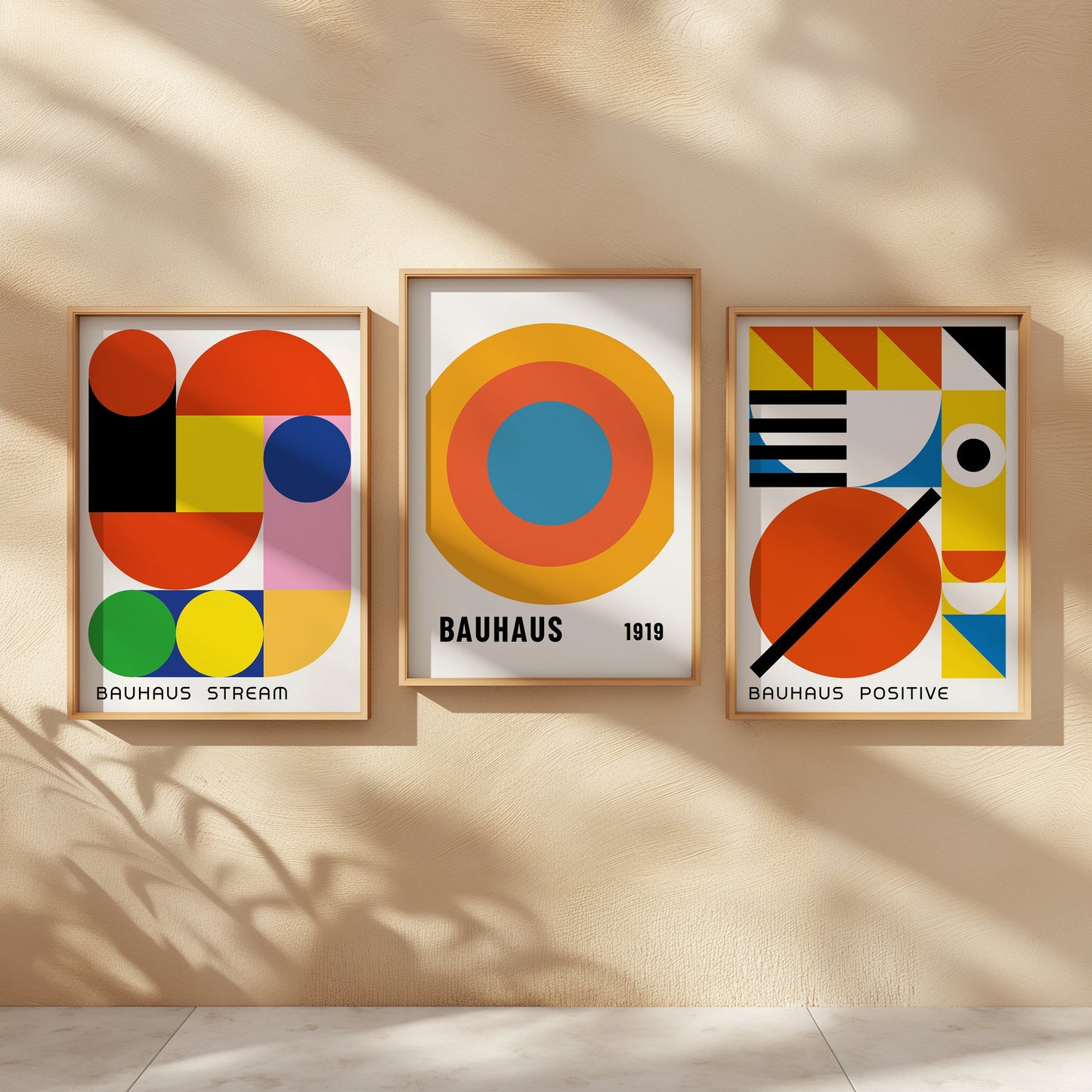 A set of three vibrant Bauhaus posters featuring geometric abstract designs in bold colors, displayed in wooden frames on a warm beige wall. These prints bring the iconic Bauhaus aesthetic to any space with their striking visual appeal.