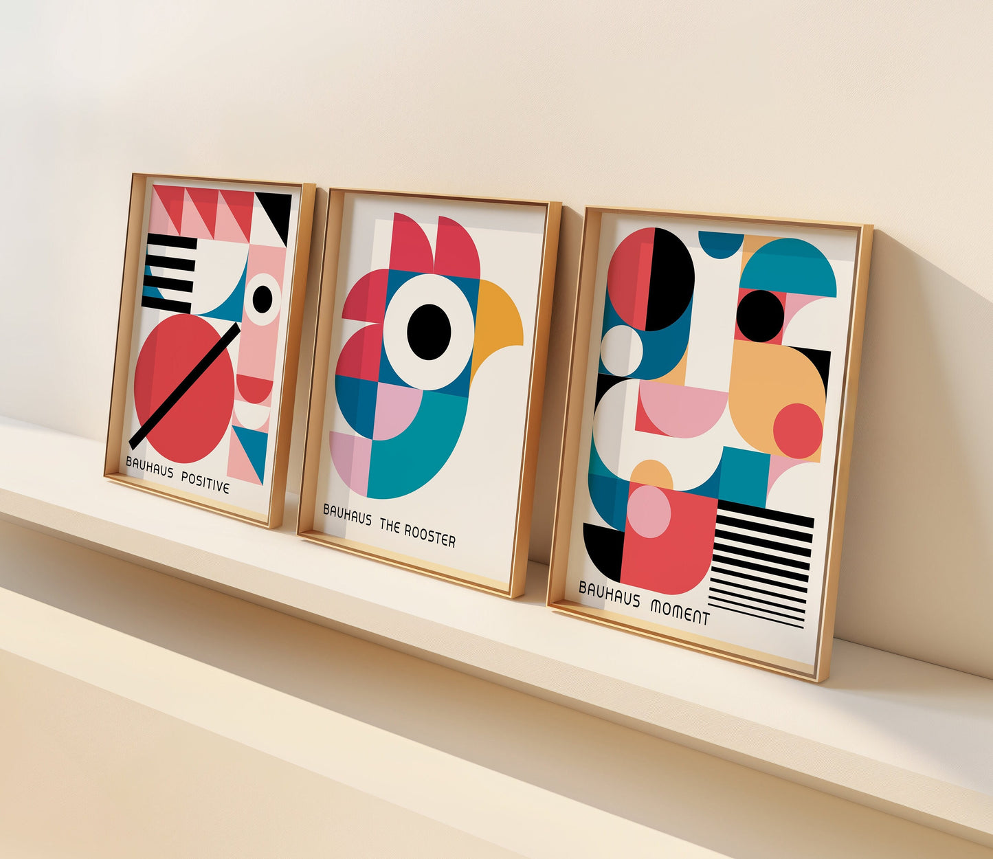 A set of three Bauhaus-inspired posters featuring a modern geometric design with themes of a rooster, positive vibes, and moment. The prints, framed and set on a wooden floor, highlight bright and bold colors,