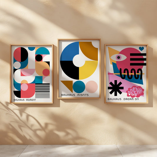 A trio of Bauhaus-inspired posters showcasing modern geometric designs with themes of Misfits, Dream On, and Moment. The prints, framed and hung on a textured wall, display bold shapes and vibrant colorS