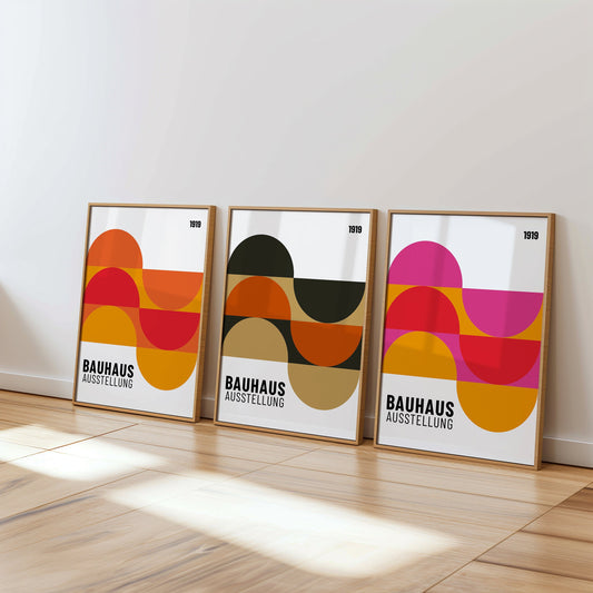 A set of three Bauhaus posters featuring abstract geometric shapes in vibrant colors. The posters are framed and displayed in a cozy, well-lit living room with wicker chairs and natural decor elements, perfect.