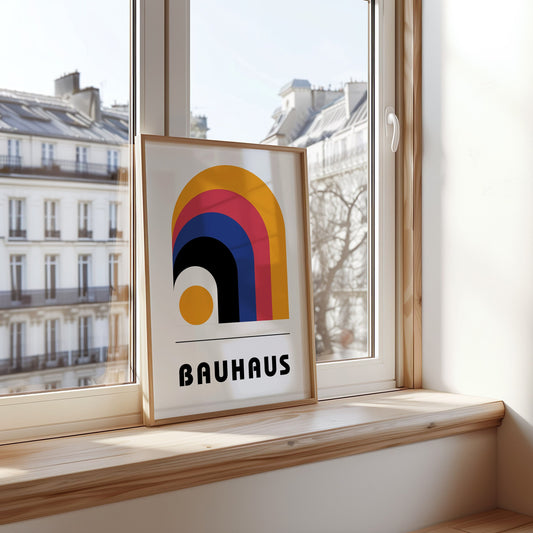 A vibrant Bauhaus-inspired poster featuring a bold, abstract rainbow arch design in shades of yellow, blue, red, and black, displayed in a modern kitchen with fresh ingredients and warm lighting.