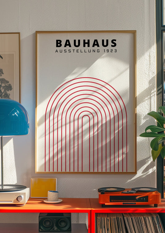 A minimalist Bauhaus-inspired poster featuring a bold red geometric arch design, framed in black, displayed in a modern kitchen setting with natural light and complementary red accents.