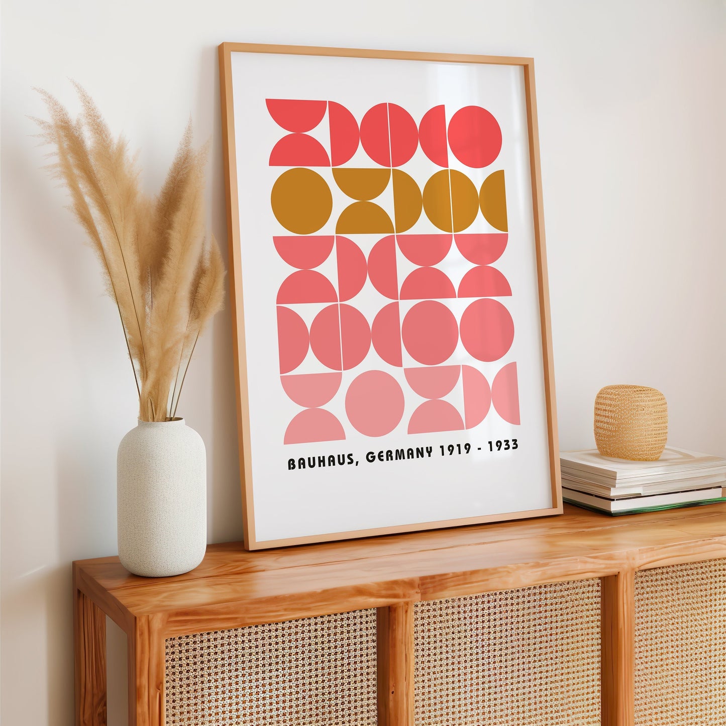 A modern Bauhaus-inspired geometric print featuring abstract shapes in pink and mustard colors, elegantly displayed on a kitchen counter with contemporary decor, fresh tomatoes, and a bowl of fruits.