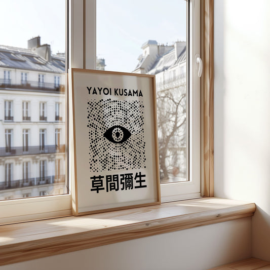 A Yayoi Kusama-inspired poster with black dots forming an abstract eye design, displayed in a cozy room setting.