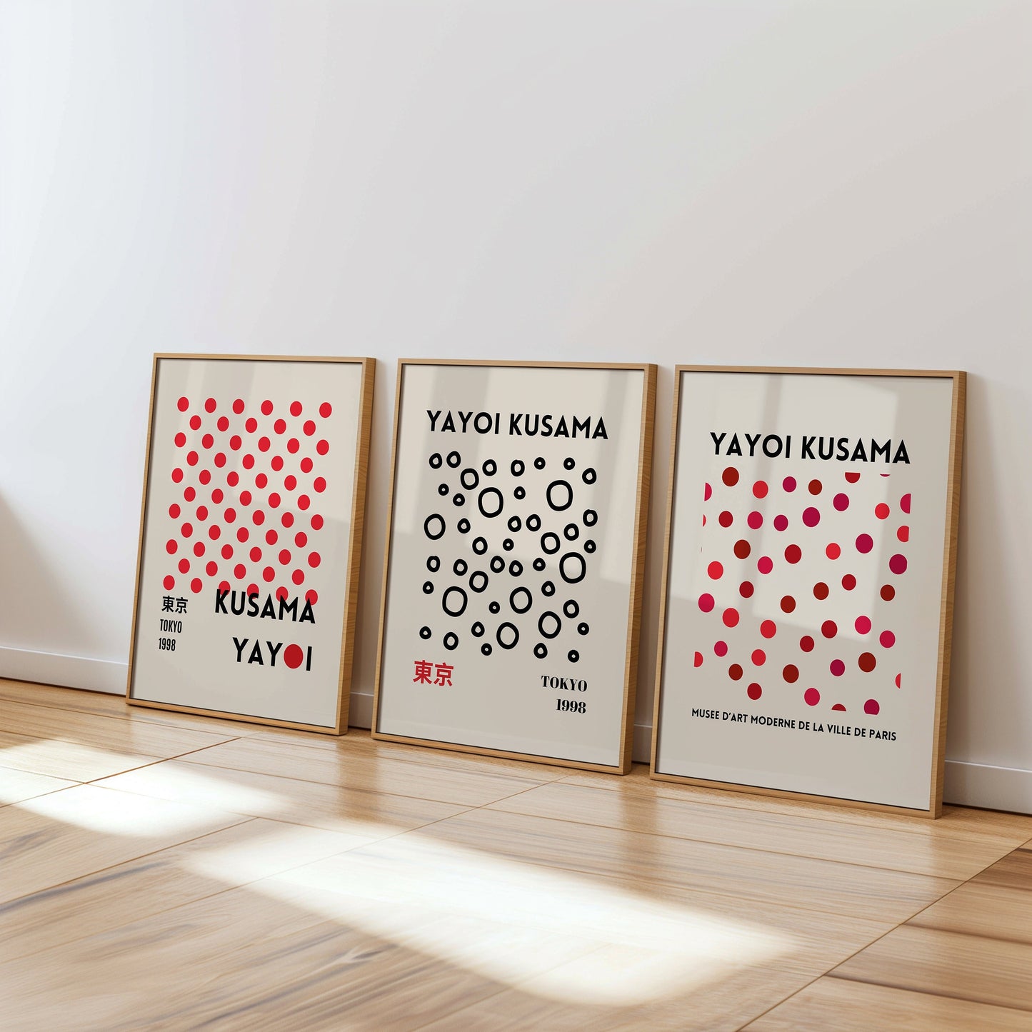 A set of three Yayoi Kusama abstract posters featuring red and black dot patterns, arranged in a minimalist style and displayed in wooden frames on a textured wall.