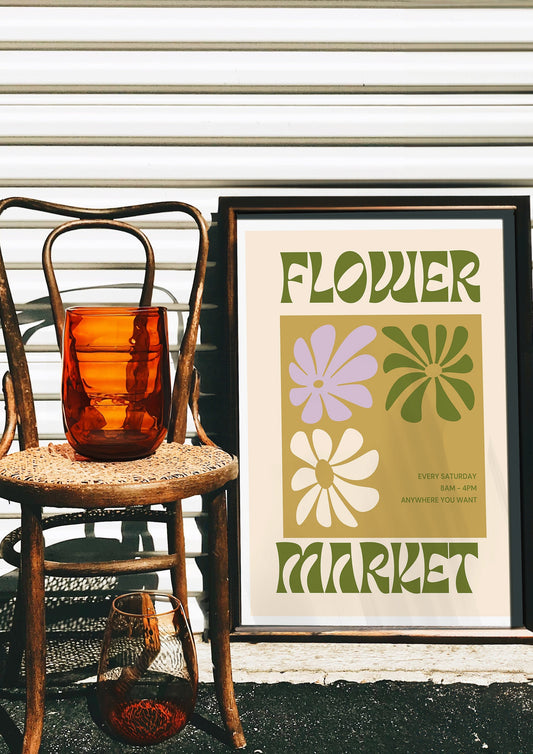 A retro-inspired;Flower Market; art poster featuring stylized floral illustrations in muted tones of green and purple. The vintage design, with bold 70s-style typography.