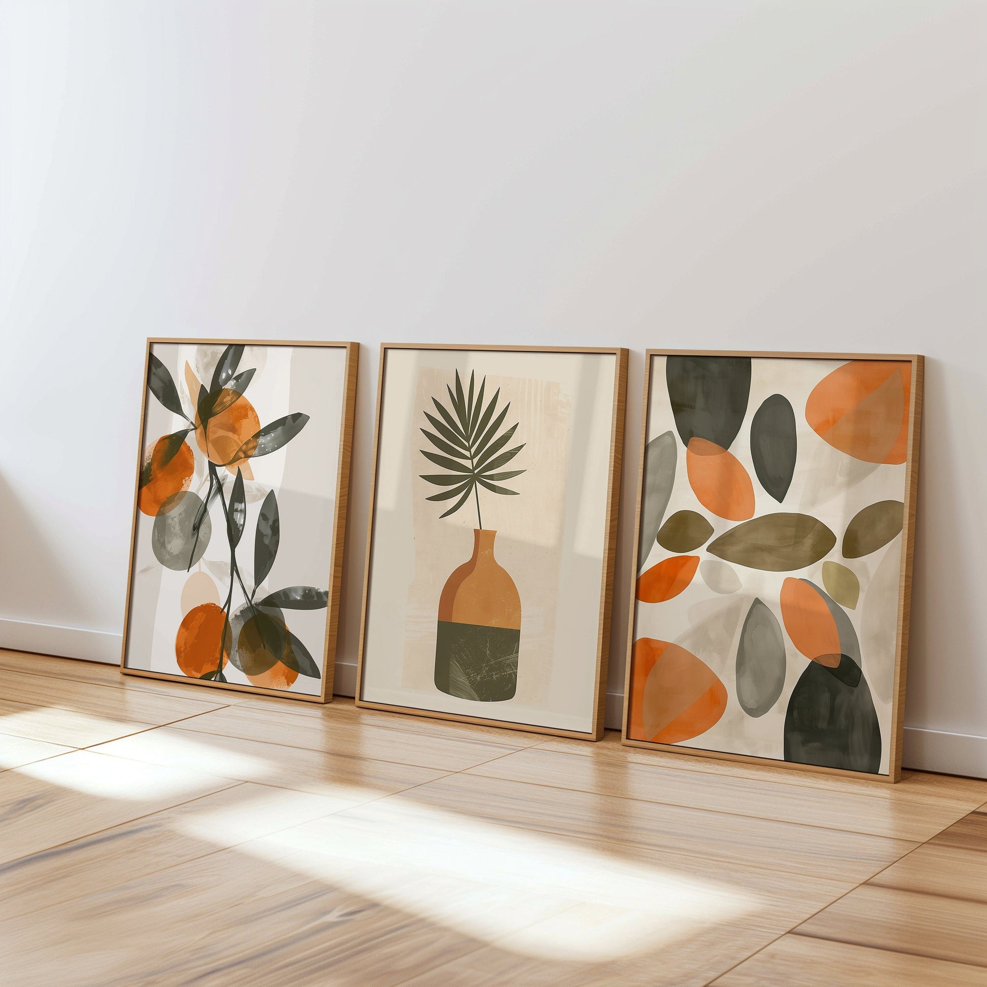 A set of three modern abstract botanical posters featuring minimalist designs with orange and green leaves, adding a fresh and natural vibe to any living space.