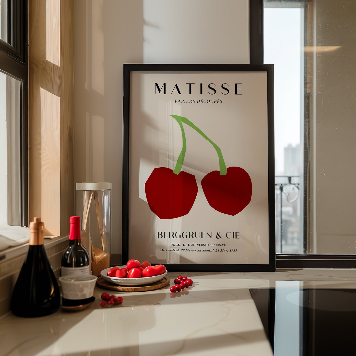 A minimalist poster of two large red cherries by Henri Matisse, displayed on a modern kitchen wall.