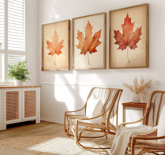 A set of three minimalist autumn wall prints featuring orange maple leaves against a soft beige background, ideal for adding a seasonal touch to a bedroom or living space.