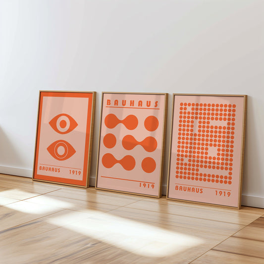 A set of three Bauhaus style posters in vibrant orange, featuring abstract geometric designs including eyes, circles, and dots. Perfect for modern and minimalist home decor.