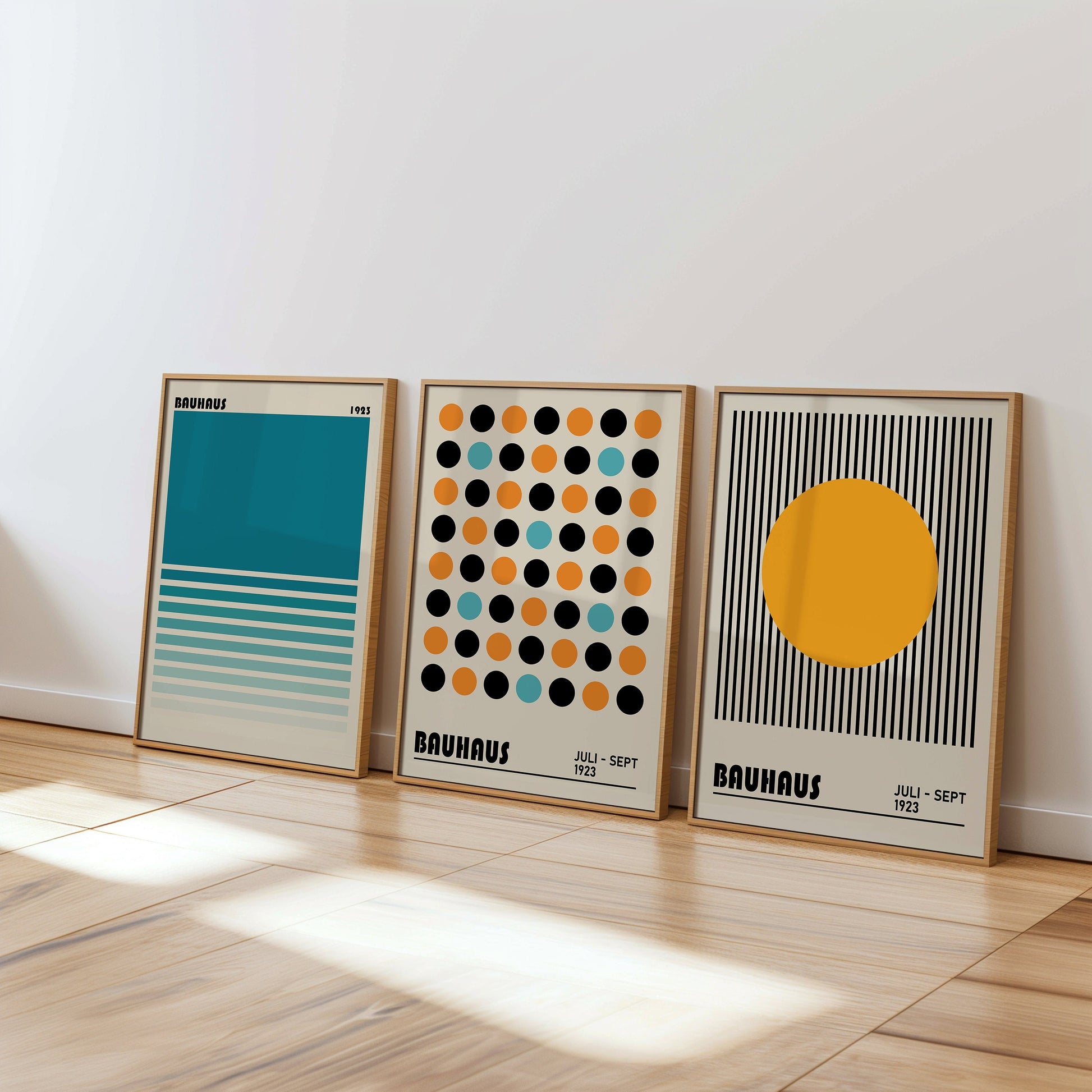 A set of three Bauhaus posters featuring modern geometric designs in teal, orange, and black on a beige background, framed in light wood. The posters display iconic Bauhaus patterns, ideal for adding a touch of modernism to any living space.