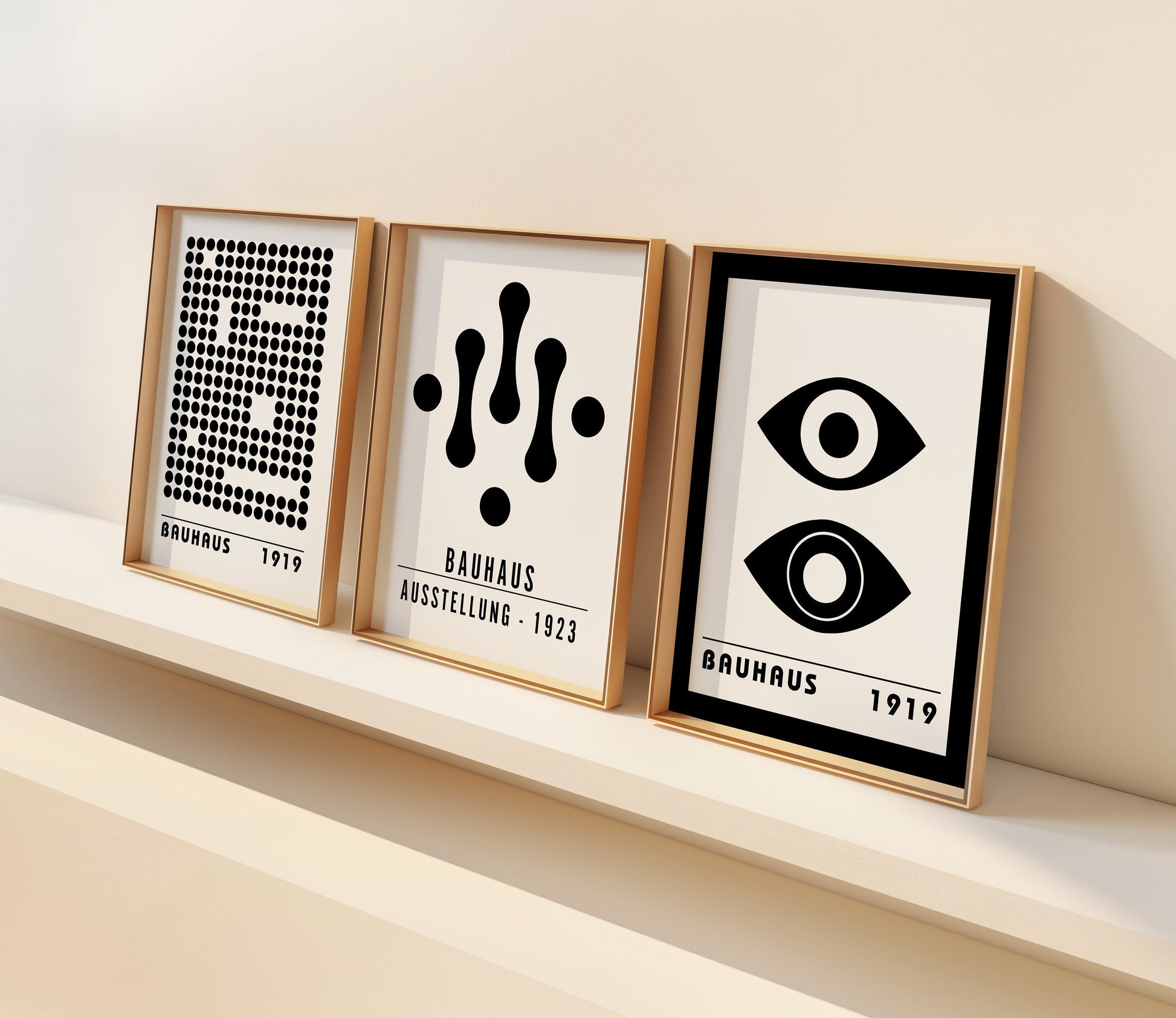 A set of three black and white Bauhaus posters featuring geometric designs from the 1919 and 1923 Bauhaus movements. The prints include an eye graphic, an abstract droplet design, and a dotted pattern, all displayed in a modern, light-filled room.