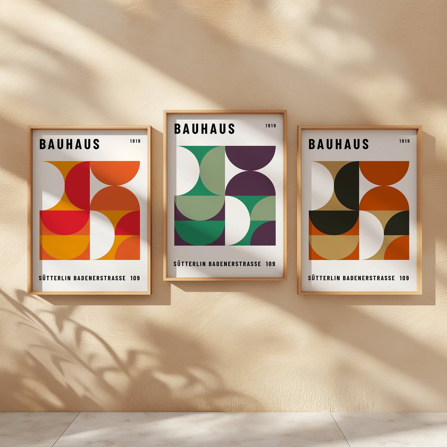 A set of three Bauhaus-inspired posters featuring vibrant geometric designs with semi-circles and curved shapes in orange, green, purple, and earthy tones, elegantly framed and displayed on a beige wall.