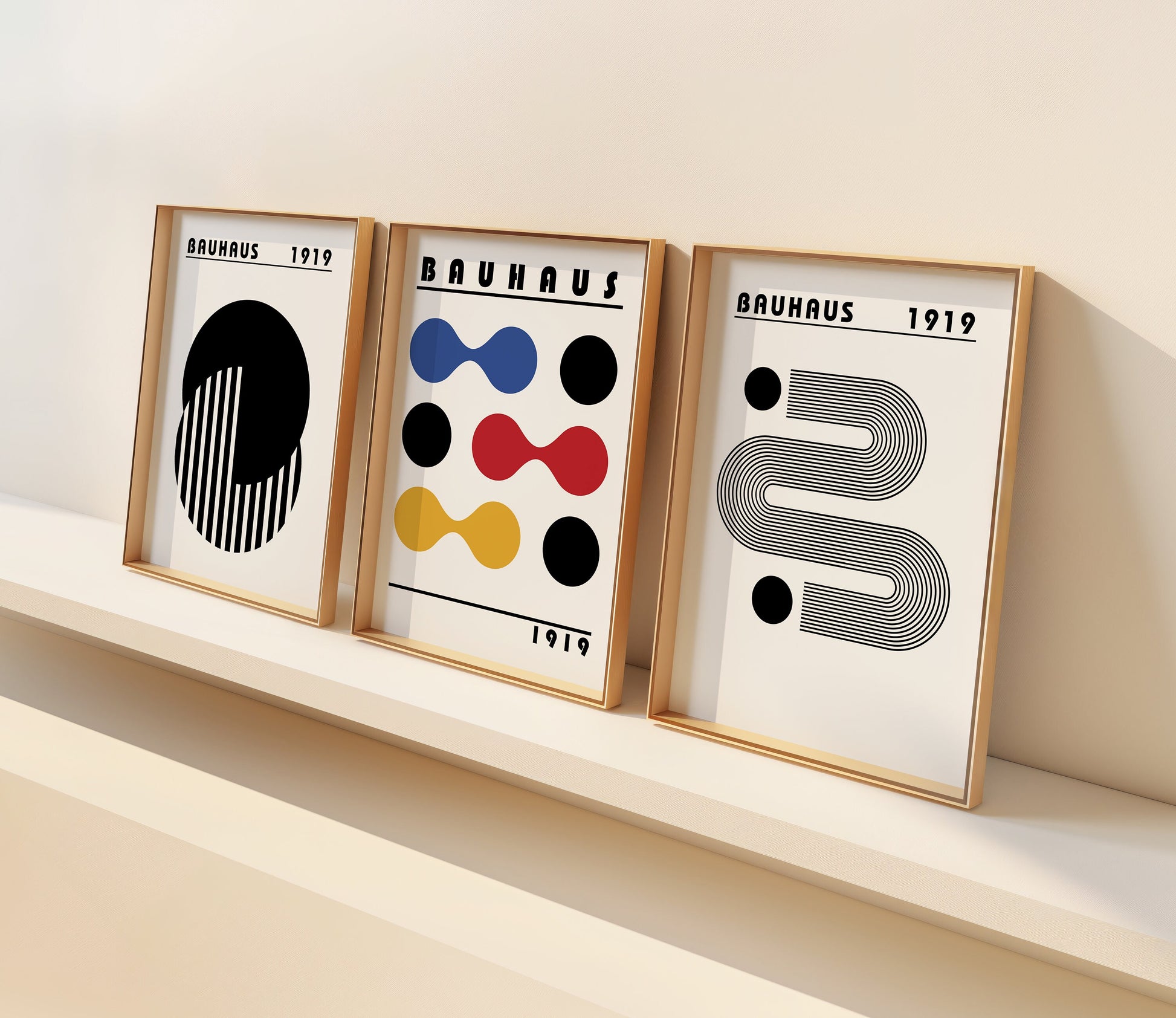 A set of three Bauhaus posters featuring abstract geometric designs in black, white, red, blue, and yellow, framed in sleek wooden frames, adding a touch of modern minimalist style to any interior space.