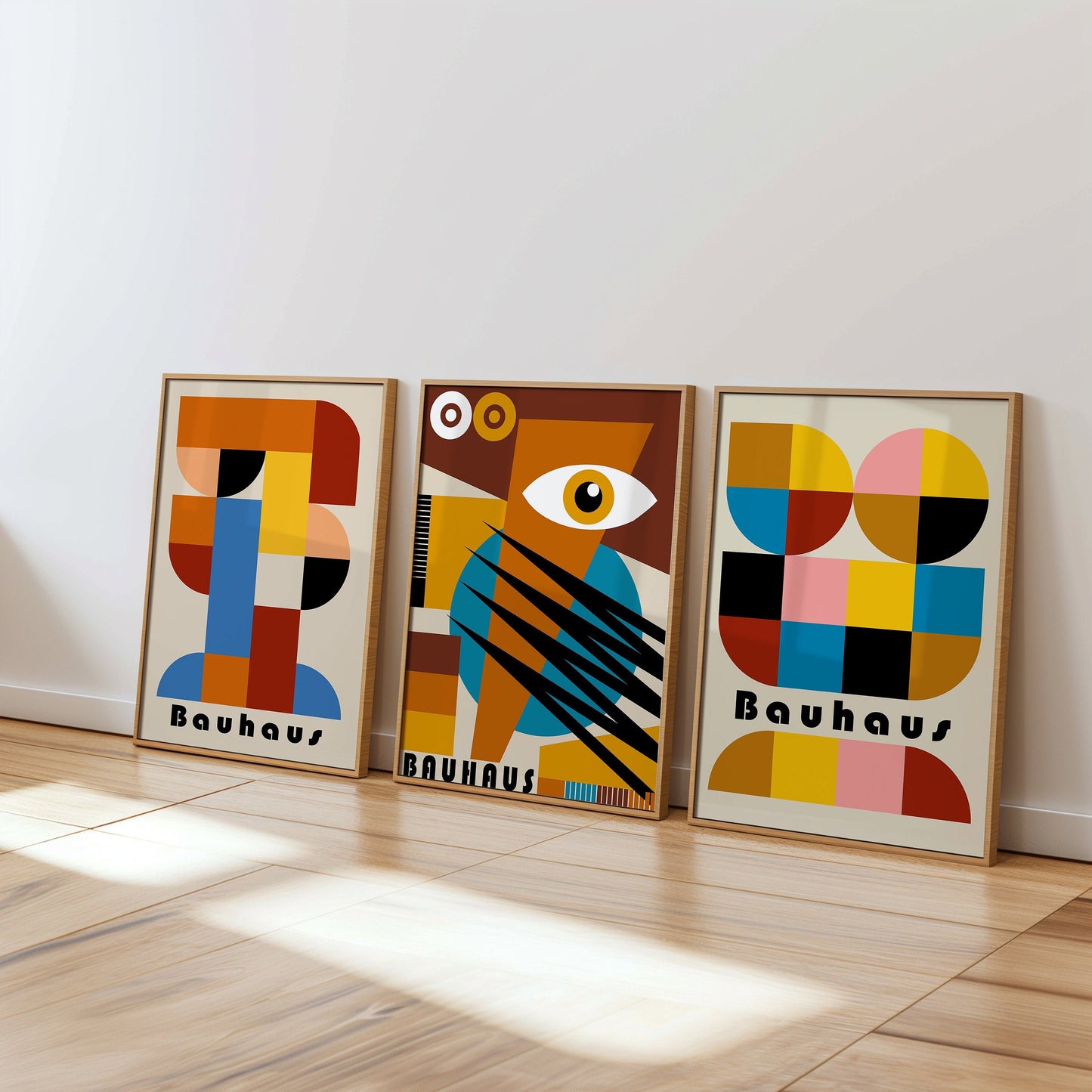 A vibrant set of three Bauhaus posters featuring colorful abstract designs with geometric shapes. The prints are framed and displayed on a wooden floor, adding a lively and artistic touch to the room.