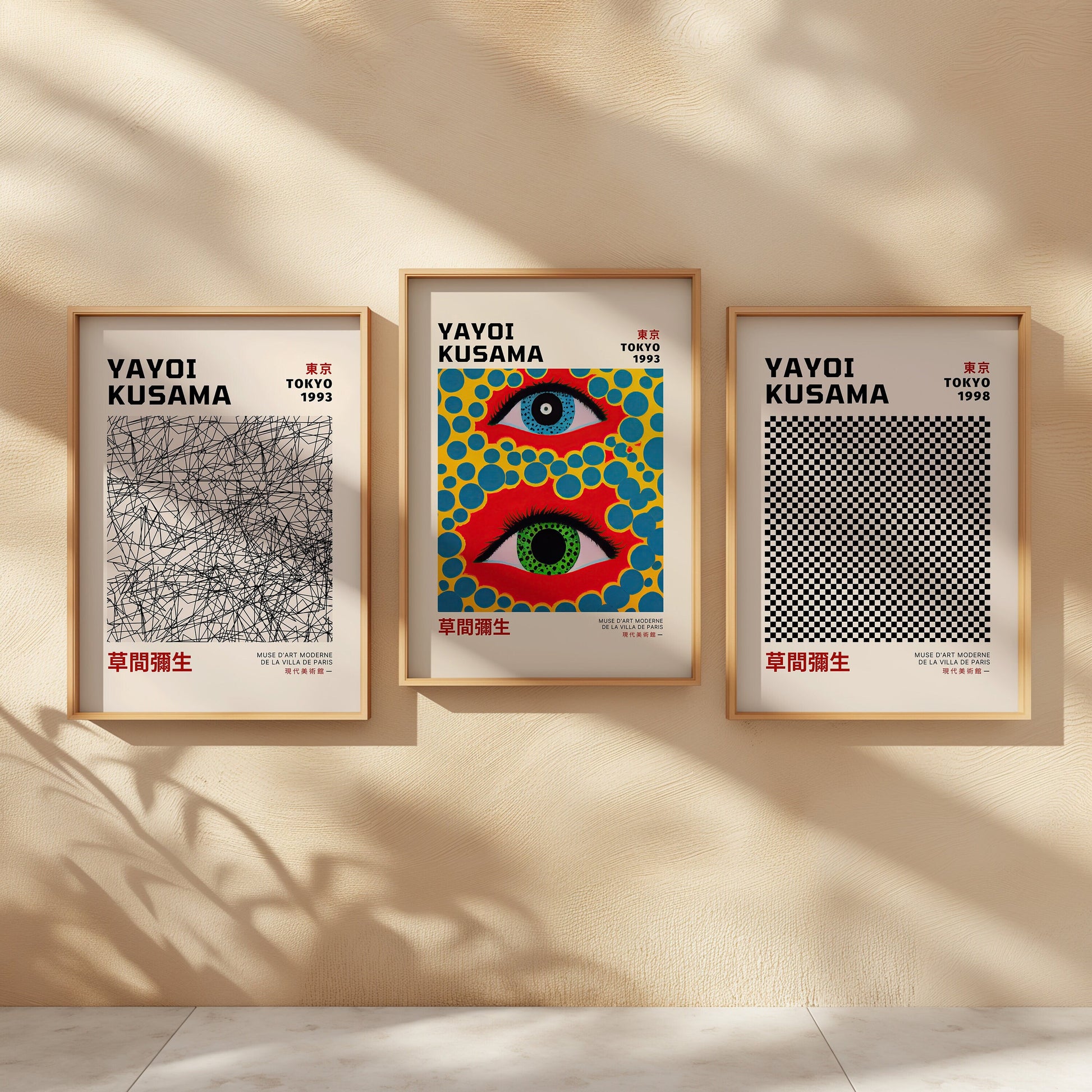 A set of three framed Yayoi Kusama posters displayed against a neutral wall. The first poster showcases a black linear abstract design from Tokyo 1993