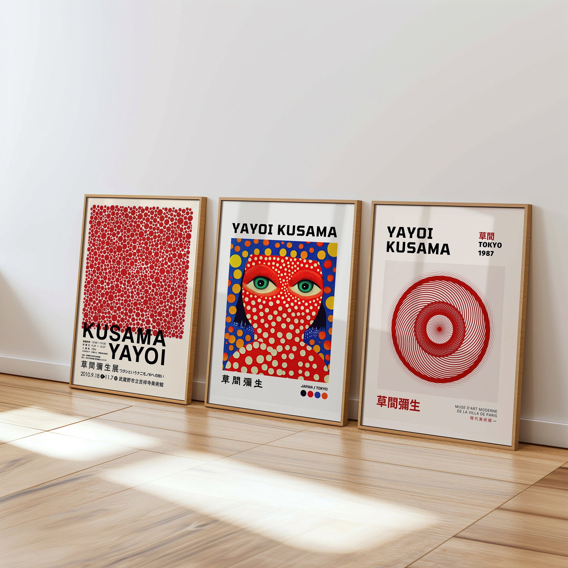 Three framed Yayoi Kusama art prints displayed against a bright, minimalist wall. The first features red polka dots densely arranged, the middle print shows Kusama&#39;s signature face covered in polka dots with vivid colors,