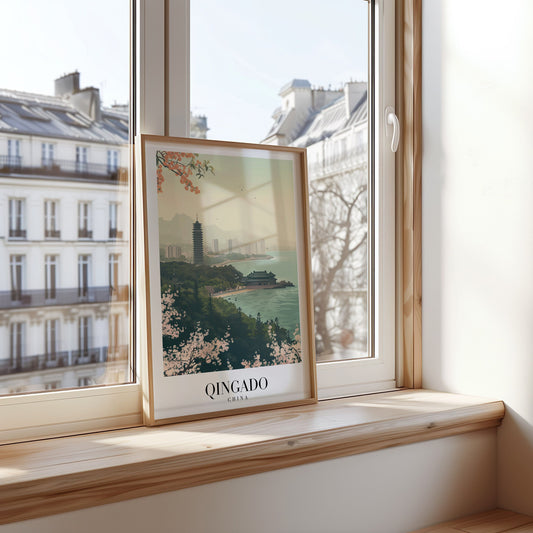 A framed poster showcasing Qingdao, China, featuring a traditional pagoda by the seaside, with a backdrop of a modern city skyline and cherry blossoms in the foreground.