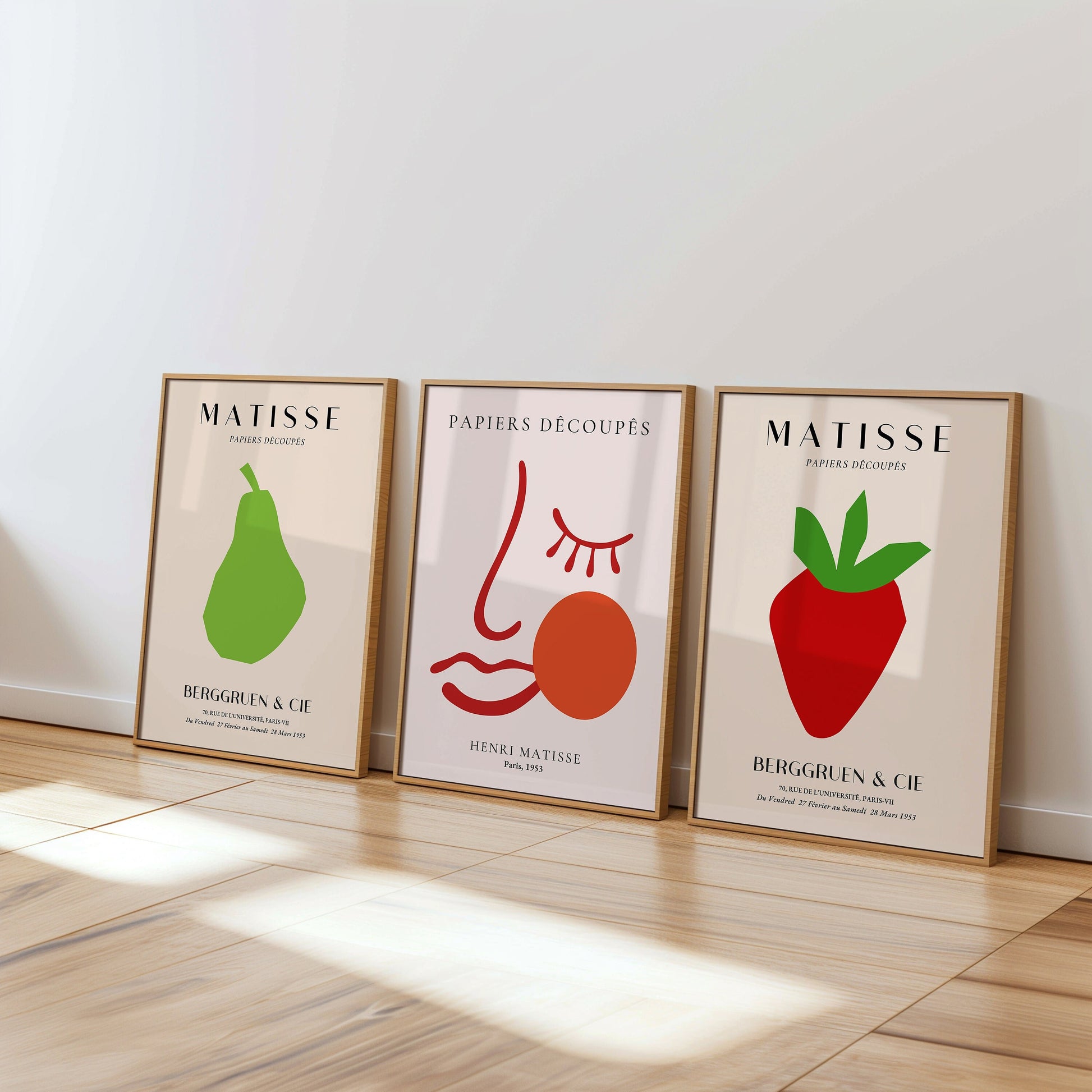 A set of three Henri Matisse posters featuring a strawberry, abstract face, and pear in bold minimalist designs from the Papiers Découpés collection, perfect for modern wall decor.