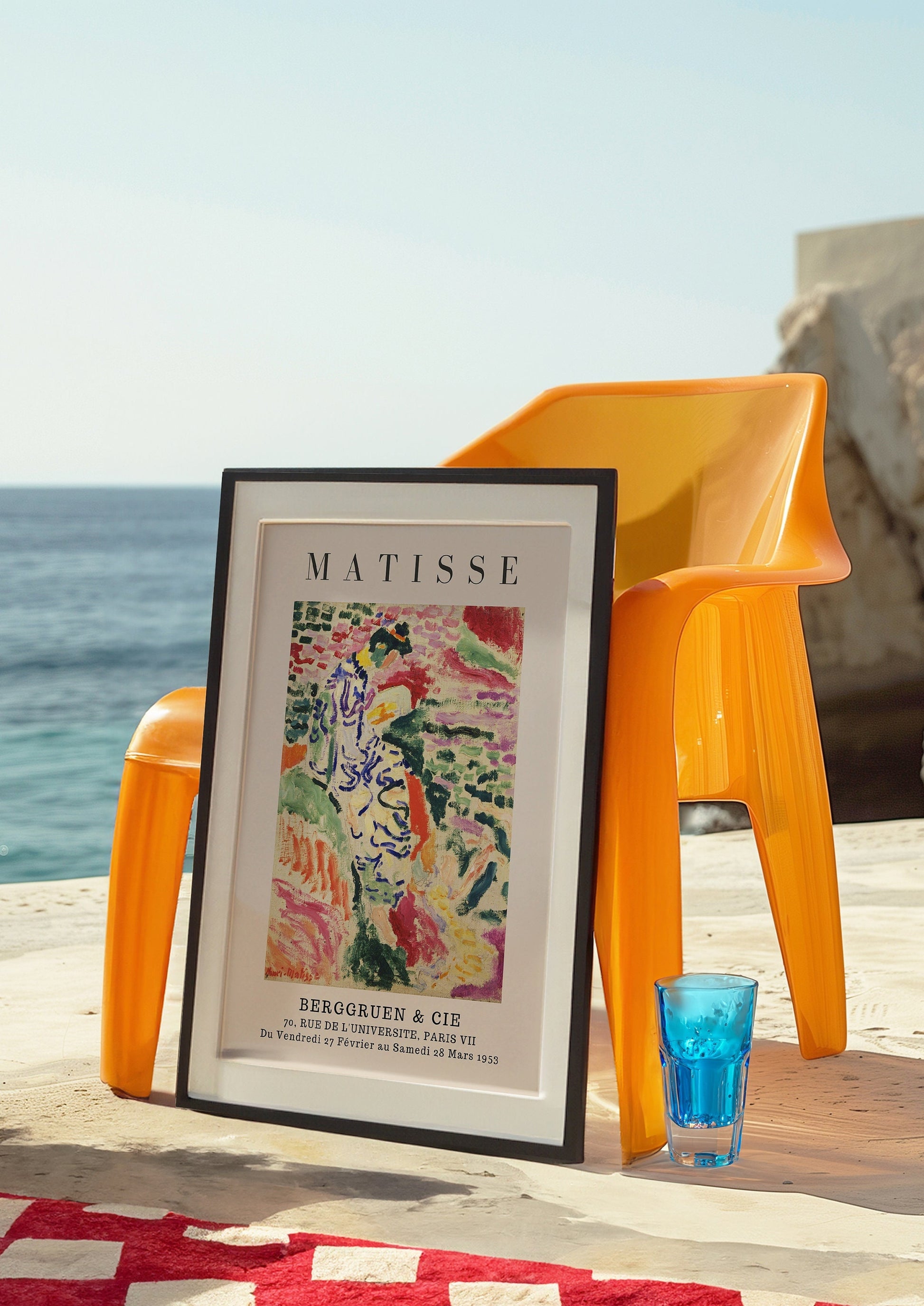 A Henri Matisse art poster displayed against an orange chair by the sea, featuring vibrant colors and a coastal theme.