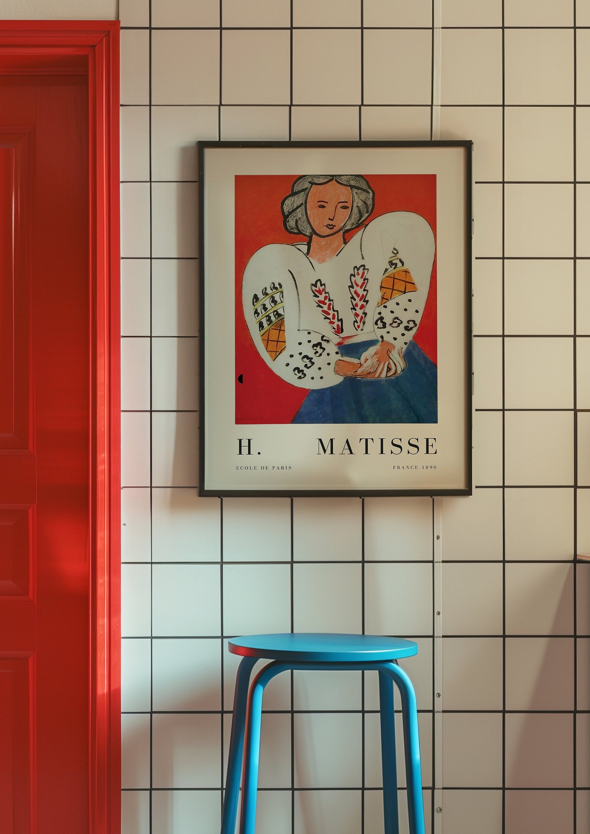 A Henri Matisse art print featuring a portrait of a woman in a white blouse with red and blue accents, framed and displayed against a tiled wall.