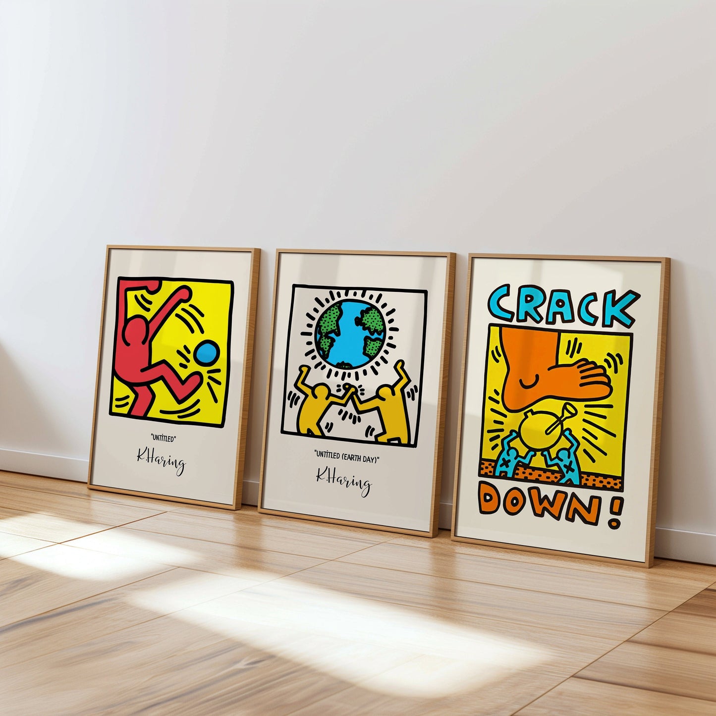 A set of three Keith Haring posters: &quot;Untitled,&quot; &quot;Untitled Earth Day,&quot; and &quot;Crack Down,&quot; presented in sleek wooden frames on a minimalistic wooden floor.