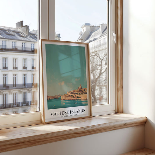 A framed poster of the Maltese Islands, featuring a peaceful seaside view of historic buildings against a turquoise Mediterranean sea.